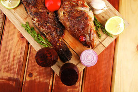 main portion of two grilled fish served on wooden table with castorsの写真素材