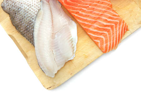 pieces of salmon , red tuna, and sole fish on wooden plate isolated on white backgroundの写真素材