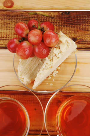 grapes with tea and cake on wooden tableの写真素材