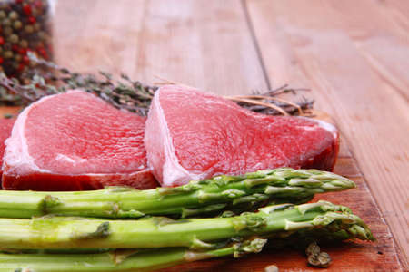 meat food : raw beef fillet on cutting board with asparagus and thyme bundle , with color peppercorn mix and red paprika powder mixed with dry spices ready to cookingの写真素材