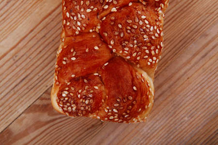 fresh loaf of light wheat bread topped by sesame seeds over wooden table
