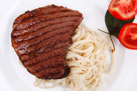 italian food : pasta with tomato on basil and roasted sirloin beef  steak on plate isolated over white backgroundの写真素材
