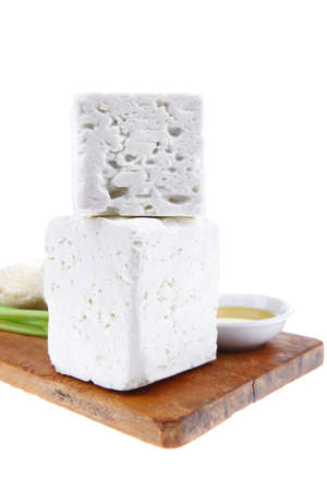 dairy product : fresh raw white soft greek feta cheese cubes and round on wooden plate isolated over white backgroundの写真素材