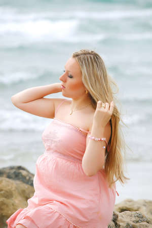 Portrait of a young beautiful blond pregnant woman at beach   on sea background の写真素材