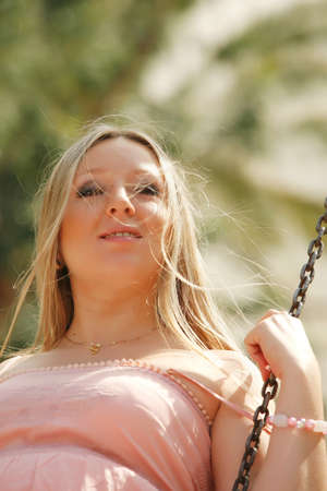 A young pregnant blond woman playing on a swing set   outdoor の写真素材