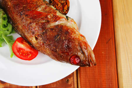 savory on plate : roast golden fish served on fish plate with lemon tomatoes and spices