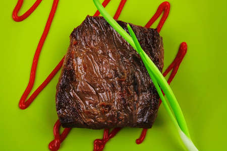 meat food : roast beef fillet mignon served on green plate with chives and ketchup isolated over white backgroundの写真素材