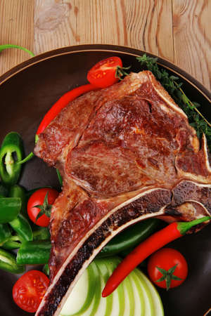 savory : roasted beef spare rib on dark dish with cutlery thyme pepper and tomato on wooden tableの写真素材