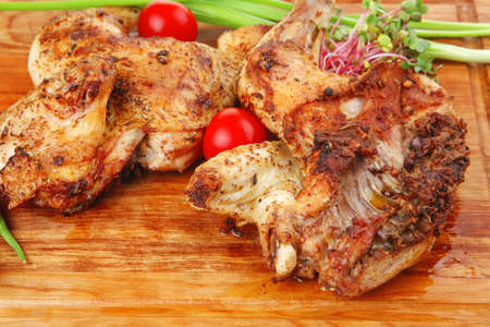 grilled meat : chicken quarters garnished with green sprouts and red peppers on wooden plate isolated over white backgroundの写真素材