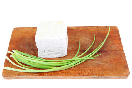 dairy food : feta white cheese cubes over small cut wooden plate isolated over white backgroundの写真素材
