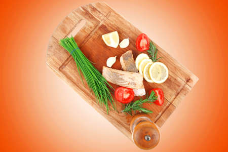 savory sea fish entree : roasted salmon fillet with green onion, red cherry tomatoes pieces, glass pepper grinder, rosemary twigs and lemon on wooden board isolated on white backgroundの写真素材