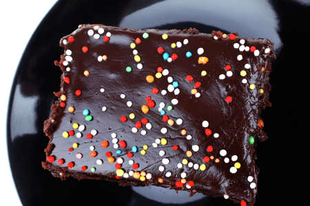 sweet food : chocolate cake coated with chocolate on black saucer isolated over white backgroundの写真素材