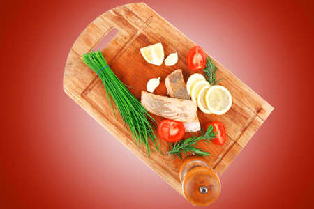 savory sea fish entree : roasted salmon fillet with green onion, red cherry tomatoes pieces, glass pepper grinder, rosemary twigs and lemon on wooden board isolated on white backgroundの写真素材