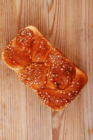 fresh loaf of light wheat bread topped by sesame seeds over wooden tableの写真素材