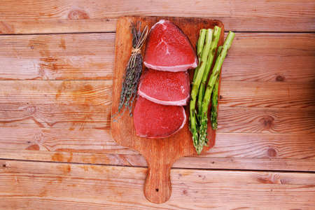 meat food : raw beef fillet on cutting board with asparagus and thyme bundle , with color peppercorn mix and red paprika powder mixed with dry spices ready to cookingの写真素材