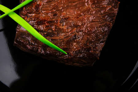 meat food : roast beef fillet mignon served on black plate with chili pepper isolated over white...