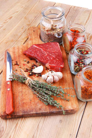 fresh raw beef meat fillet flesh with peppercorn and thyme ready to grill on wood figured old style board  over table with spices in glassの写真素材