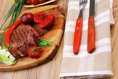 barbecued meat : beef ( lamb ) garnished with green lettuce and red chili hot pepper on wooden table with cutleryの写真素材