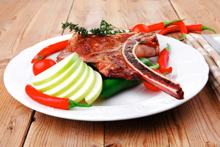 savory : roasted beef spare rib on white dish with cutlery thyme pepper and tomato on wooden tableの写真素材