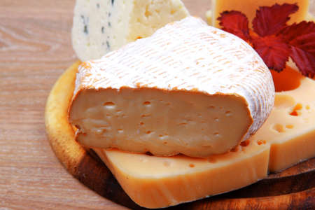edam parmesan and brie cheese on wooden platter over wooden table