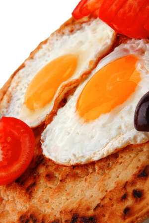 fried eggs on pancake with tomato and olives