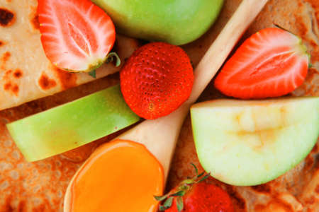 baked and fruits : pancake with honey strawberries and apple isolated over white background on wooden plateの写真素材