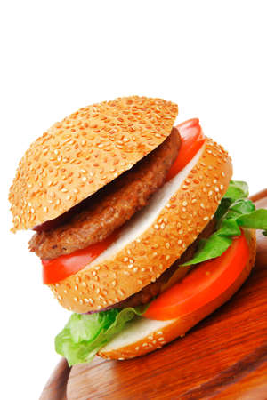 big double roasted hamburger on wooden plate with cutlery isolated  over white backgroundの写真素材