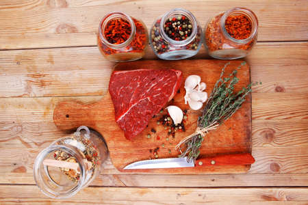 raw beef meat fillet with peppercorn and thyme and differnt spices in glass bottles ready to grill...