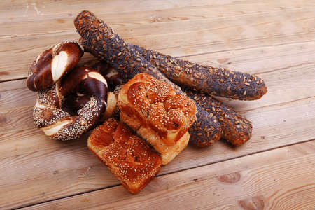 fresh mix of baguettes , pretzels and wheat bread, on wooden table