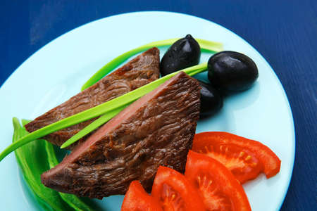meat food : roast beef fillet mignon served on blue plate with chili pepper and tomatoes over blue wooden tableの写真素材