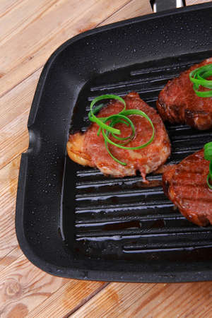 fresh grilled beef fillet strips on black grill plate over woodの写真素材