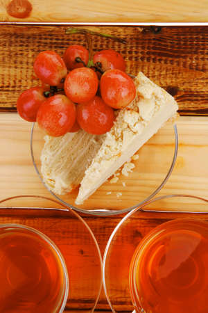 grapes with tea and cake on wooden tableの写真素材
