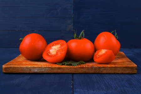 raw vegetables : raw ripe tomatoes ready to prepare on cutting board over blue table