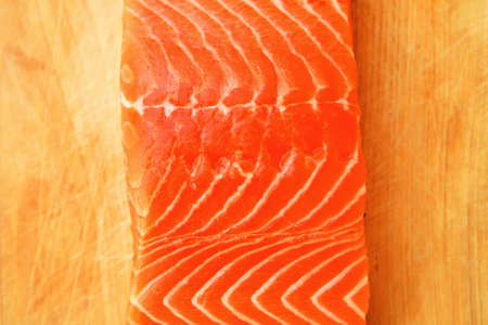 piece of fresh raw salmon on wooden tray isolated on white backgroundの写真素材