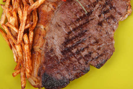 main course : grill beef steak with potato chips and fresh cherry tomato , dry red hot chili peppers on green plate isolated on white backgroundの写真素材