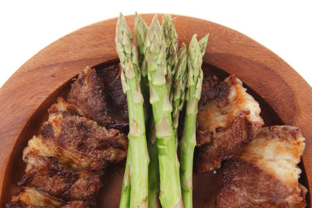 dinner of hot grilled beef meat ribs served with asparagus on wooden plate isolated on white backgroundの写真素材