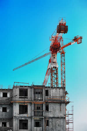 a large lifting crane at the building site near a building under construction 
