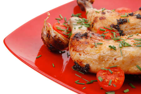 served grilled chicken legs with tomatoes lemon and thyme on red plate isolated on white backgroundの写真素材