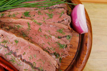 beef slices on wooden plate with peppers on wood