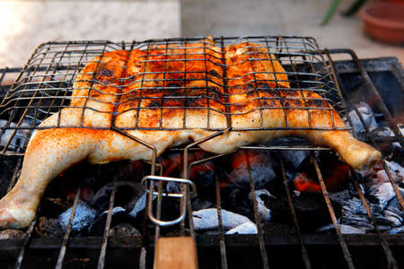 grilling spiced chicken in grid on charcoal bbq with tomatoes and vegetablesの写真素材