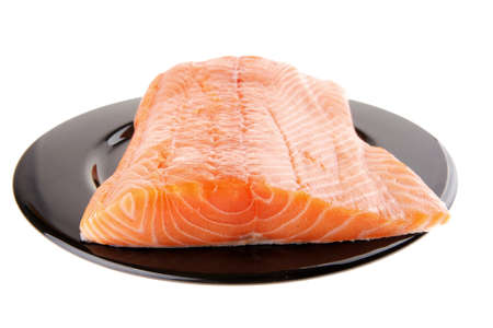big salmon chunk on black plate over whiteの写真素材