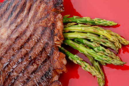 meat table : grilled beef fillet with asparagus served on red dish isolated over whiteの写真素材