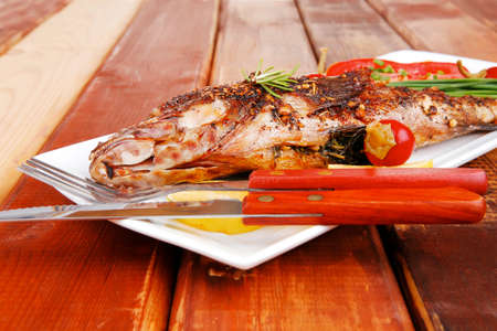 savory on wood: whole fryed sunfish over plate with tomatoes lemons and peppersの写真素材