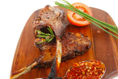 meat savory on wooden plate: roast ribs with peppers tomato and dry spices isolated on white
