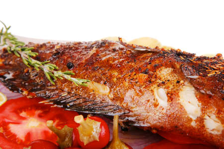 served main course: whole fried seabass served on plate with lemons,tomatoes and peppersの写真素材