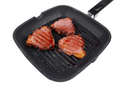 fresh grilled bloody beef steaks on black grill plate isolated on white backgroundの写真素材