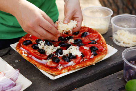 prepare hand made pizza with olives and tomatoes on wooden table on picnic with different kind of...