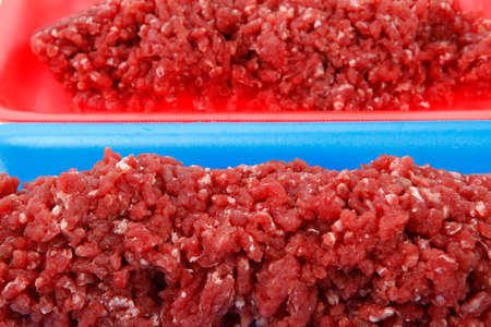 fresh raw mince beef meat on red and blue tray's isolated over white background