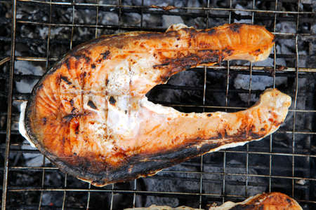 grilling salmon steak with milk cream in grid over barbecueの写真素材