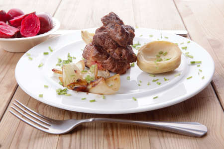 beef bourguignon in wine with artichoke and marinated vegetables on white plate over wooden tableの写真素材